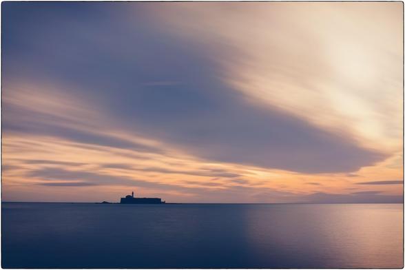 Photographie de la mer. Une île avec un fort. Au coucher du soleil en exposition longue
