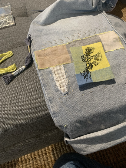 Mending jeans with linen patches one with a black stamp of a hand holding a flower