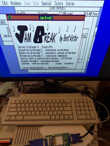 Another photograph of an Apple IIgs computer, this time from above at a steep angle.  The computer is running the Desktop Accessory "Jam Break" by Bret Victor.  The program shows instructions for typing on the computer keys to produce synthesized electric guitar notes and riffs.  The picture is very clean and stable.