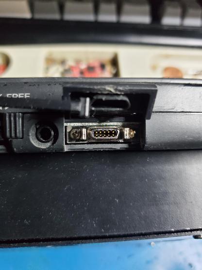 Closeup of the side of the previously mentioned PDA, with a slim 10-pin port that looks like it accepts a card edge with a D shell and some clips.