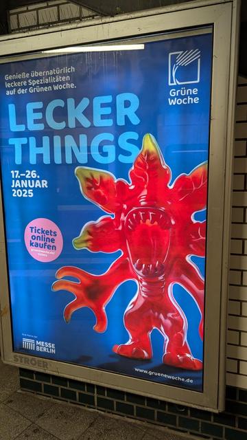 Zu sehen ist eine Reklametafel mit Werbung für die Grüne Woche in Berlin. Darauf abgebildet ist eine rote Figur aus Weingummi in Form eines Monsters aus der Fernsehserie "Stranger Things". Über der Figur ist der Slogan "Lecker Things" gedruckt.