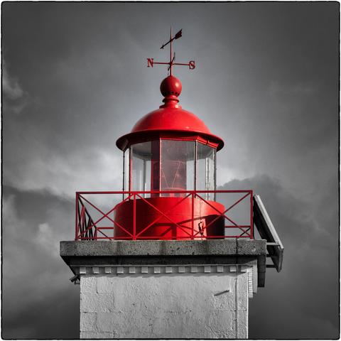 Quadratische Fotografie des oberen Teils eines Leuchtturms, Schwarzweiss Aufnahme mit Selektivfarbe rot.