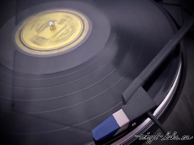 Auf dem Plattenteller ist eine schwarze Vinyl mit gelbem Etikett zu sehen. 