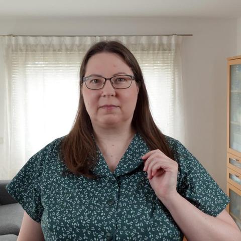 Close up of a woman in a green dress with leeves pattern and a cut on collar