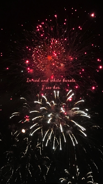Bright red and white fireworks illuminate the night sky, creating a canvas of transient beauty and reflection.
