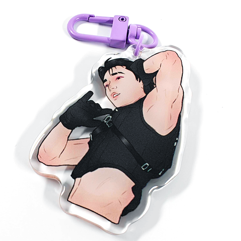 A picture of an acrylic keychain of San from ATEEZ, with short black hair, a black crop top and black gloves. He has his left arm up and you can see his armpit. The keychain has a light purple clasp.