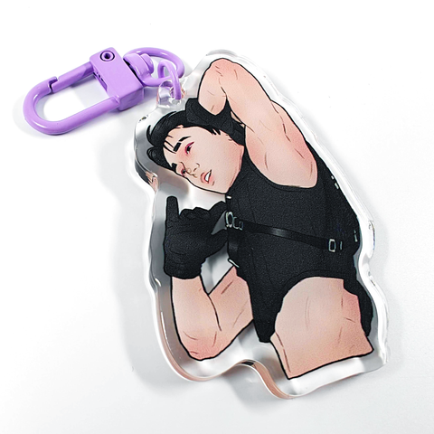 A picture of an acrylic keychain of San from ATEEZ, with short black hair, a black crop top and black gloves. He has his left arm up and you can see his armpit. The keychain has a light purple clasp.