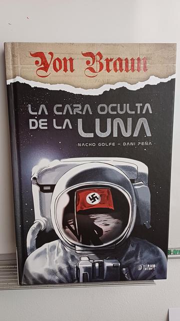 Caratula de la novela gráfica Titulada "Von Braun. La cara oculta de la Luna" Primer plano de un austronauta en la Luna en cuyo casco se refleja la bandera nazi.