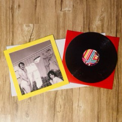 Das Vinyl ist schwarz mit einem bunt gestreiftem Etikett, dass zu dem Cover passt. Auf der Rückseite des Covers ist eine Fotografie mit zwei Menschen zeigt.