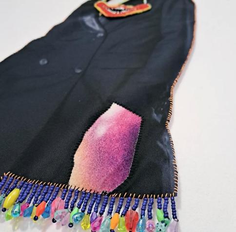 Silhouette en assemblage textile : crâne qui pleure, collier sourire carnassier, veste de smoking, mains voix lactée, bordure perlée (détail)