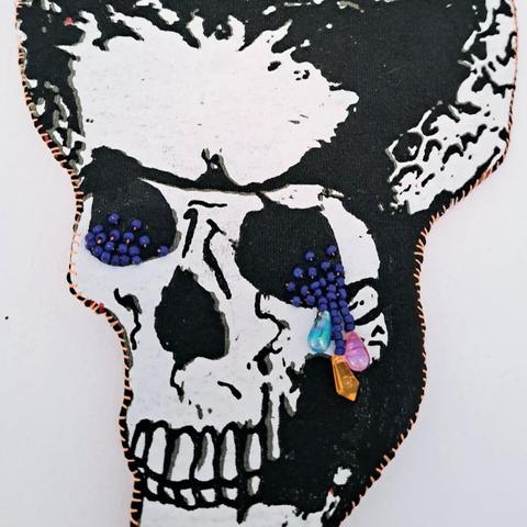 Silhouette en assemblage textile : crâne qui pleure, collier sourire carnassier, veste de smoking, mains voix lactée, bordure perlée (détail)