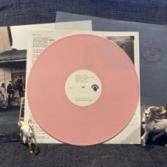 Die Vinyl ist hellrosa opak mit einem beigen Etikett