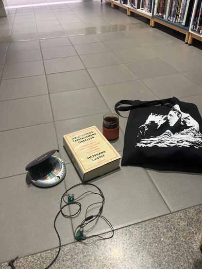 Objects on floor in library. Discman, Sondre Lerche totebag, Zuboff book and Kokkokaffe