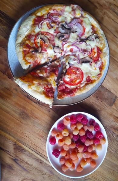 Auf einem hölzernen Tisch liegt eine halb gegessene Pizza auf einem hellblauen Teller. Die Pizza ist mit Tomatensauce, Käse, Champignons und roten Zwiebeln belegt. Neben dem Teller mit der Pizza liegt ein kleiner weißer Teller mit einer Mischung aus roten und gelben Himbeeren.

Bereitgestellt von @altbot, generiert mit Gemini