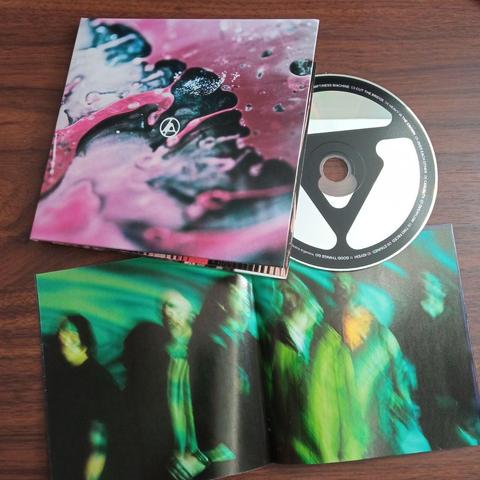 Se muestra contenido físico del álbum: además del mismo estuche cerrado, un CD con el nuevo logo de Linkin Park en color negro (el logo es similar al redondo con letras "LP" usado desde Minutes to Midnight, pero con líneas más gruesas y vértices redondeados). Un booklet abierto muestra la fotografía de la banda estilizada con un desenfoque de movimiento.
