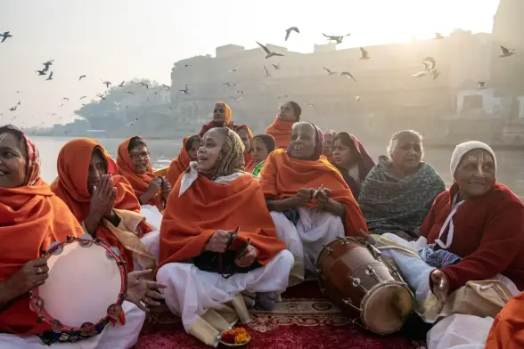 Women enjoy a peaceful morning boat ride on the Yamuna River, singing religious songs