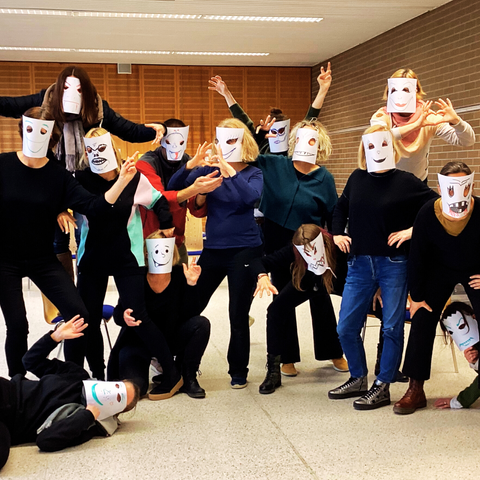 Gruppenbild Menschen mit Papiermasken mit lachenden, weinenden, bösen aufgemalten Gesichtern