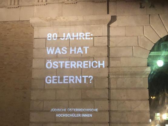 Part of the Burgtor with projection of the following words: 80 Jahre  - was hat Österreich gelernt?