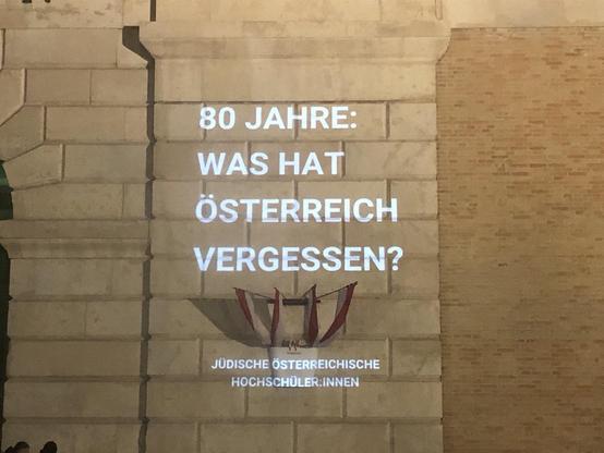 Part of the Burgtor with projection of the following words: 80 Jahre  - was hat Österreich vergessen?