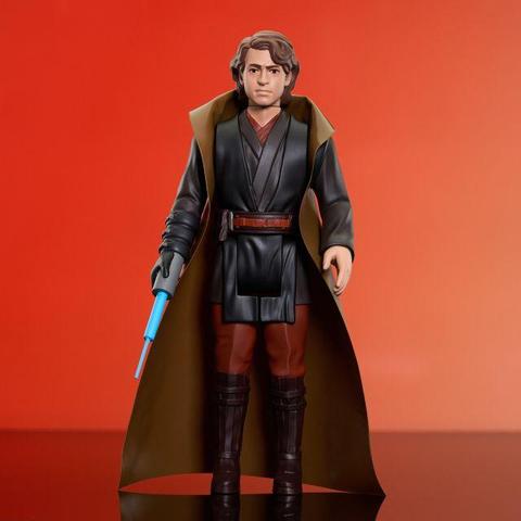 Photo de la figurine Jumbo d'Anakin Skywalker façon Kenner. Le fond de l'image est rouge. Anakin a une tenue noire et rouge. Son bras droit comporte le sabre-laser bleu rétractible. Il a des bottes marron. Sa ceinture est rouge. Et sa cape est marron clair.