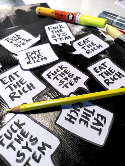 Ein Häufchen aus Papier ausgeschnittener Sprechblasen, die jeweils „Fuck the system“ oder „Eat the rich“ verkünden.