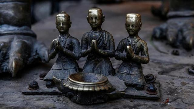 Three small bronze figures kneeling with hands in anjali.