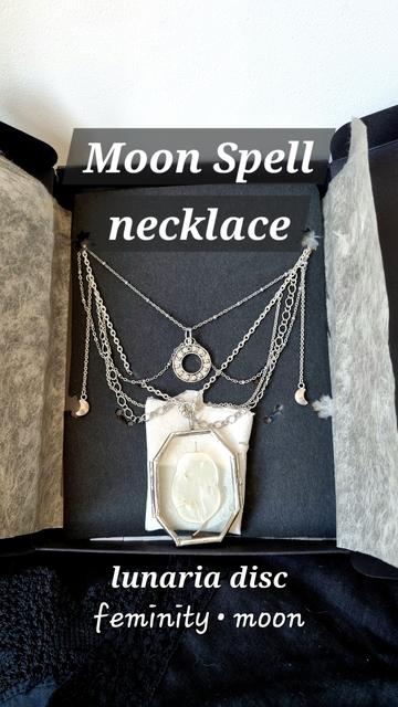The necklace to be won seen closer with its name written (“Moon Spell”), what it contains (a “lunaria disc”, the latin name of the Honesty) and its symbolism (“femininity, moon”). We can better see the small crescent moons that fall on the sides of the necklace, the moon phase charm that falls in the hollow of the neck, the detail of the different chains and the glass pendant with its unique lunaria disc.
