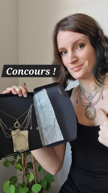 Une femme montre du doigt son collier constitué de cascades de chaînes argentées avec des breloques de croissants de lune, une breloque avec les phase de la lune en cercle et en pièce centrale un pendentif en verre renfermant une silique de Monnaie du Pape (lunaria annua) aux reflets nacrés comme la lune.
Dans l’autre main elle a une élégante boîte en carton noir dans laquelle est enchassé un collier semblable.
Il est écrit “Concours” en gros car le collier dans le carton est à gagner.
