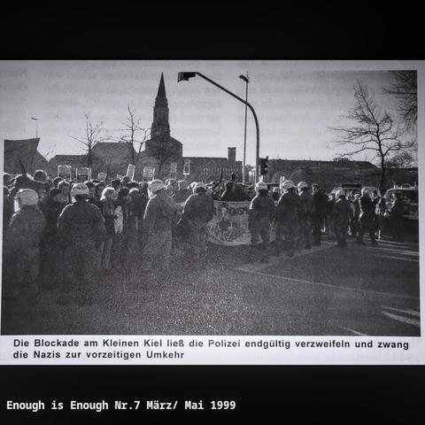 Eine Polizeikette steht vor einer Blockade am kleinen Kiel. Unter dem Bild steht "Die BLockade am Kleinen Kiel ließ die Polizei entgültig verzweifeln und zwang die Nazis zur vorzeitigen Umkehr"