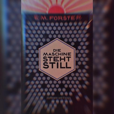 Cover des Buchs "Die Maschine steht still" von E. M. Forster.

Dunkelviolett gehalten. In der Mitte befindet sich ein beigefarbenes Sechseck worin "Die Maschine steht still" in Großbuchstaben steht. Der Hintergrund besteht aus zahlreichen hellviolettfarbenen Sechsecken. Der obere Rand ist eine rote stilisierte Sonne worunter "E. M. Forster" steht.