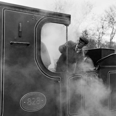 A man leans out the side of the driver's "cabin" on a steam engine. I don't know if he's the driver or the fireman. I'm guessing driver. There's a lot of steam, and someone else is just about visible inside the cab in the midst of all the steam and smoke. Also, I'm pretty sure I'm using all the wrong words here. I love photographing these things, but I'm bloody clueless about them.