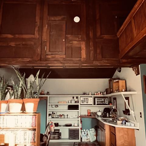 view from living room to small kitchen with top half of photo a wooden wall made from re-used wood, probably from a barn, that includes a small door, now purely decorative (I assume)