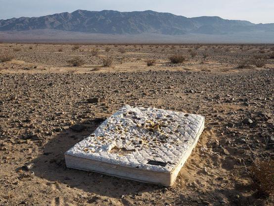 Mattress in foreground of desert landscape leading back to mountains.