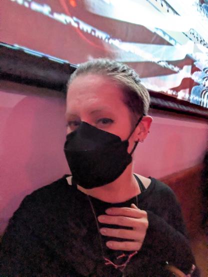 Masked non-binary woman sitting in front of a projection display