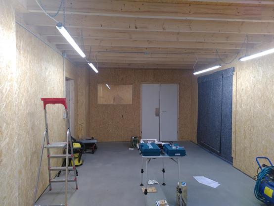 Shop interior, facing a wall with white doors and a window.
