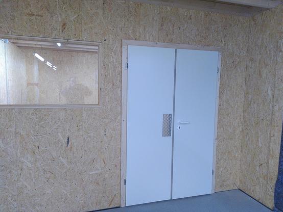 A wall with a window and white double doors.