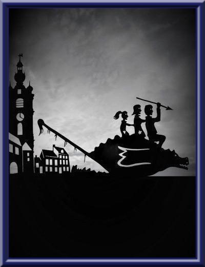 ▪️ Girouette ‘Doudou de Mons’ (beffroi, maisons typiques, dragon, enfants)
▪️ Weathervane ‘Doudou of Mons’ (belfry, typical houses, dragon, children) 
▪️ Windwijzer ‘Doudou van Mons’ (belfort, typische huizen, draak, kinderen)
▪️ Wetterfahne ‘Doudou von Mons’ (Belfried, typische Häuser, Drache, Kinder)  
▪️ Banderuola ‘Doudou di Mons’ ▪️ (torre civica, case enveloppe tipiche, drago, bambini) 
🔹 
Oeuvre: Thierry SORET, artisan d’art, girouettier 