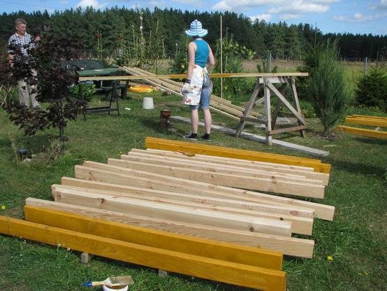 Elle a tourné le dos au petit chantier dans le jardin de la maison. Son regard a quitté le chevron qu’elle enduit au pinceau pour aller au-delà de la clôture, puis des champs, s’éloignant. Sur le sol bien vert du jardin, poutres et éléments
de charpente s’accumulent en prévision de la construction d’une large dépendance d’été, ici en bout de propriété. Elle, légèrement vêtue, short en jeans, chaussures Converse, débardeur, tablier sur la poitrine et les hanches, gants de travail, chapeau en tissu à bandes bleues et blanches par-dessus ses cheveux longs. Elle tourne le dos, le regard s’éloignant vers les forêts, là-bas après les champs, le vent qui fait bouger la cime des conifères sombres, les petits nuages blancs qui filent sur l’horizon bleu.
