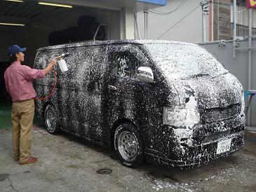 Solvant mousseux expulsé du pistolet à pression sur la carrosserie du petit van noir. Comme si cent mouettes avaient survolé le véhicule et offert leur guano, Toyota entarté. L’employé de la petite entreprise de lave-auto, une fois le solvant bien jeté sur la carrosserie, frotte énergiquement avec un gant de mouton.