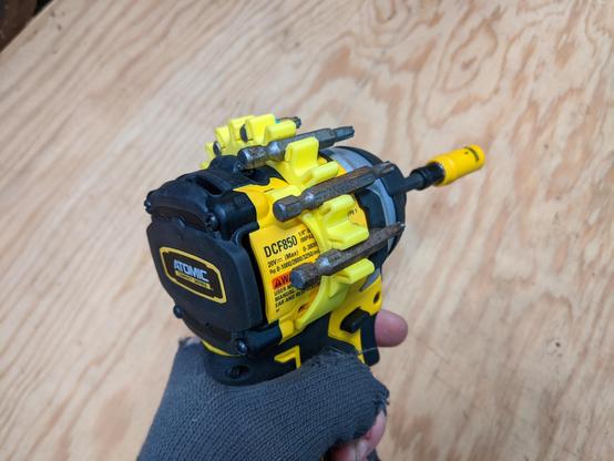 A yellow 3d printed 'bit clip' loaded with seven bits, attached securely around the bole of a dewalt impact driver.
