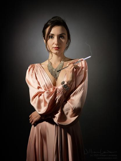 Photograph of Model Zoe Celesta West poses standing in 3/4 length view.  She is engaging the viewer.  She wears a fancy pink/salmon colored dress with a very sparkly necklace and bracelet, and she's holding a cigarette in a holder.  She has (IMHO) a very f*ck around and find out type of expression.