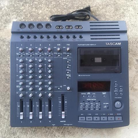 A Tascam 424mkII cassette multitrack recorder as seen from above, resting on a stone surface.