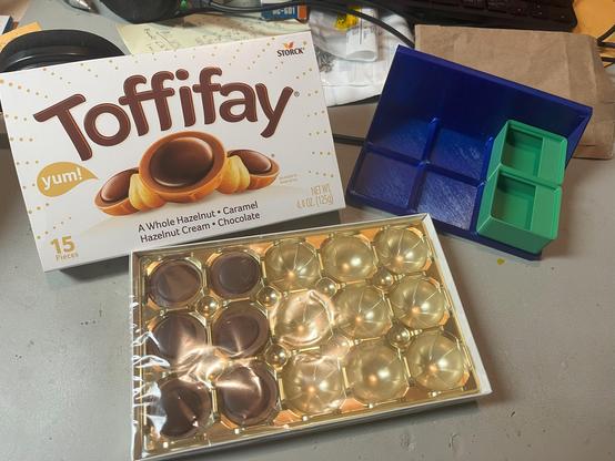 Picture of a half-eaten pack of Toffifee candy, next to some 3D-printed Gridfinity components (a grid-based storage system designed by Zack Freedman.