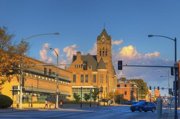 Davenport City Hall, a historic brick building with a prominent clock tower stands under a bright blue sky with fluffy clouds.
