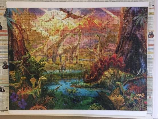 red golden mountains in the background, blue lake in the middle, group of ferns on the left, tree on the right and various types of dinos in the puzzle