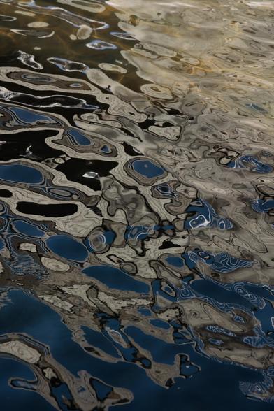 Abstract patterns of light and reflections rippling on water, showcasing blue, gray, and silver hues.
