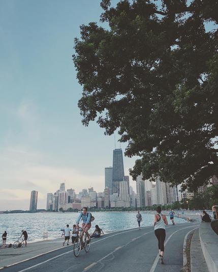 Chicago skyline as seen from the south side of North Avenue beach. Cyclists and joggers are biking and running along the bike trails that border the lakefront.