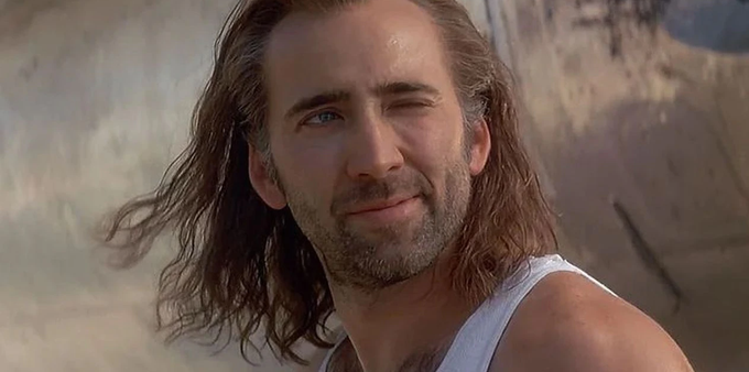 Nicolas Cage, from Con Air, long hair blowing in the wind, winking.
