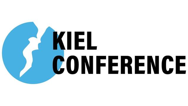 Blue circle with a white shape showing the outlines of the Kiel Fjord. Next to it the Lettering: Kiel Conference