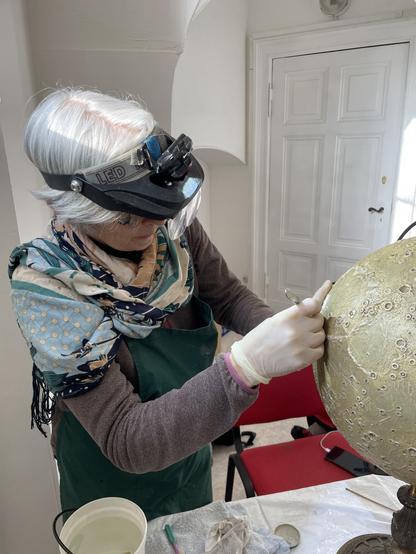 La restauratrice Florence Godinot procède in situ au nettoyage et à la consolidation du globe de la Lune de von Lade (1897)